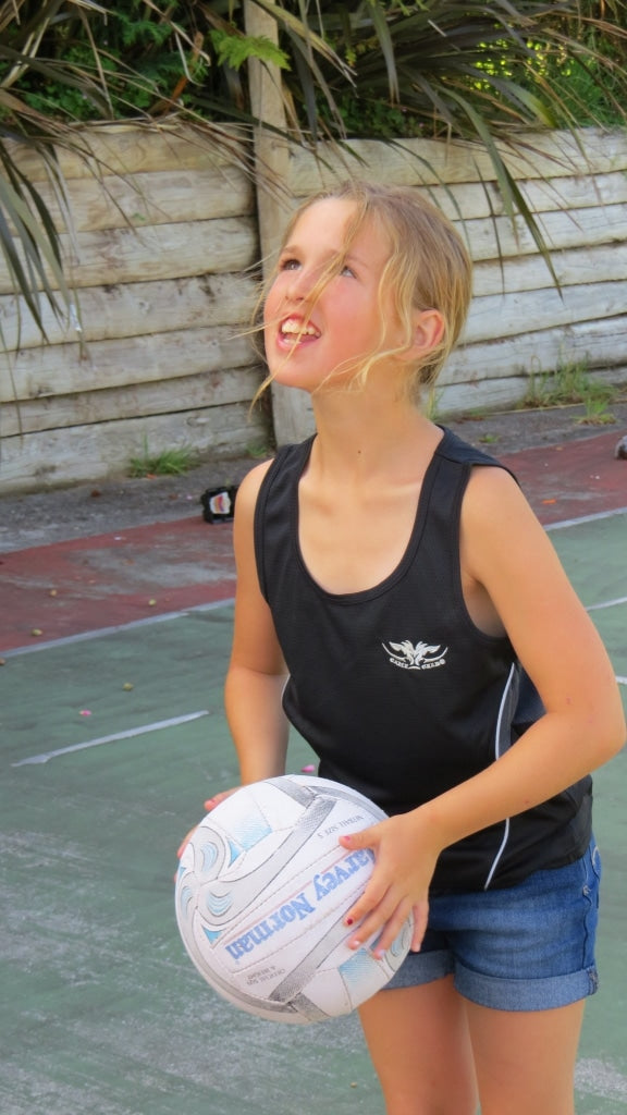 Girl wearing lightweight black quick dry singlet holding netball